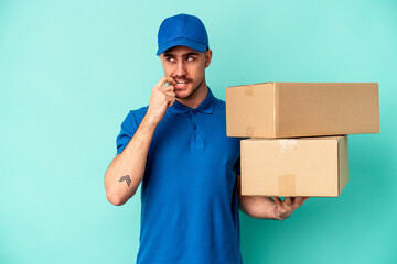 Wall Mural - Young delivery caucasian man isolated on blue background relaxed thinking about something looking at a copy space.