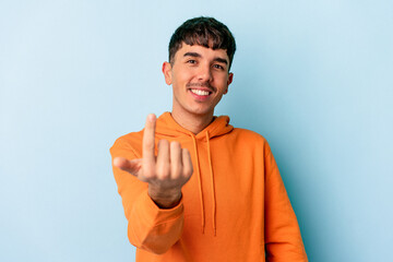 Wall Mural - Young mixed race man isolated on blue background pointing with finger at you as if inviting come closer.