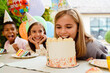 © Drobot Dean - Multiracial children making fun while eating cake during birthday party