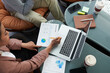 © DragonImages - Business people talking about data in report with charts and diagrams, view from the top