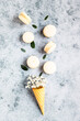 Waffle cone filled with gypsophila flowers and macarons. Pastel colors. Traditional french almond dessert with sweet filling. Top view.