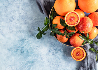 Wall Mural - Ripe juicy Sicilian blood oranges with leaves on ceramic plate, blue background.