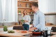 © standret - Man standing by the table. Couple preparing food at home on the modern kitchen