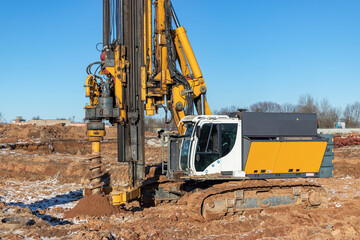 A powerful drilling rig with an auger drills a well at a construction site. Pile foundations. Bored piles.