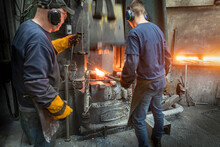 Engineer With Apprentice Forging Steel Parts In Hammer Press In Industrial Forge