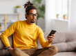© JenkoAtaman - Young focused serious african american man relaxing at home with smartphone, surfing internet