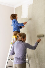 A Woman And An Eight Year Old Boy Decorating A Room, Painting Walls. 