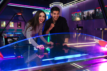 White young friends laughing while playing air hockey