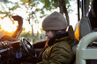 © Mint Images - A boy in a hat and coat in a jeep at sunrise on a safari drive.