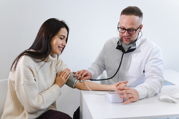 Male doctor at the medical examination measures the blood pressure of a woman patient. Woman on appointment in cardiologist