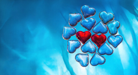 Two red hearts among blue hearts in water