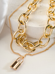 Wall Mural - Fashion bijouterie - double gold chain with a lock on a white stand