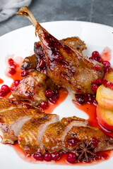 Wall Mural - Duck leg confit with berry sauce on white plate macro close up