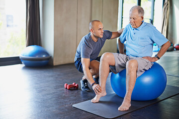 Wall Mural - Maintaining his muscles through physiotherapy. Shot of a senior man working out with the help of a trainer.