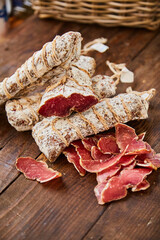 Wall Mural - Raw-dried, dried sausage sliced lies on a wooden table. Traditional dried sausage, ready to eat, delicious breakfast. The concept of handmade meat products.