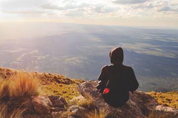 young woman on top of a mountain appreciating the landscape on a afternoon relaxed with her backpack and enjoying