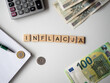 Inflacja - napis z drewnianych kostek, kryzys, wartość, cena złotówki, złoty, euro, ​kalkulator, pieniądze, długopis, flatlay