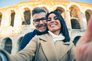 Happy couple of senior tourist having fun taking a selfie in front of famous monument of Italy - Vacation, tourism and travel concept