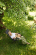 © Girts - Woman sleeping  in garden recliner chair. Summer vacation in the yard. Mature Scandinavian female life in retirement. Good living. View from the top. Beautiful middle aged woman resting