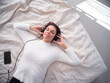© DavidMorillo - Woman relaxed on the bed with eyes closed and listening to music with the mobile