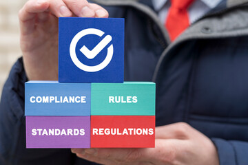 Compliance Standard Regulation Rule Business Technology Concept. Businessman holding colorful polystyrene blocks with check mark and words compliance, regulations, rules, standards.