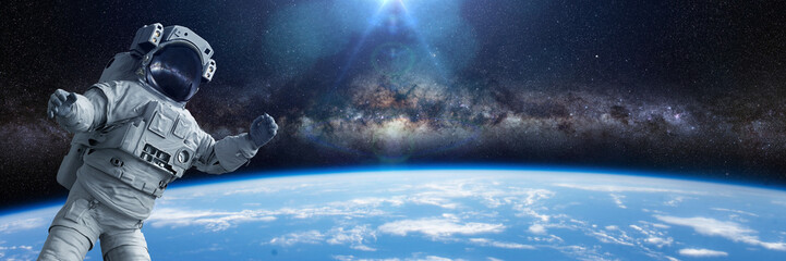 Wall Mural - astronaut during a spacewalk in orbit of planet earth, background banner with empty space