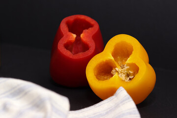 yellow, red and orange bell pepper dinner on black background with white blue striped napkin