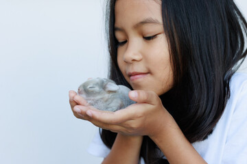 Wall Mural - Newborn baby holland lop bunny in child hands. Asian girl holding tiny bunny in hand with tenderness and love. People take care a pet. New life of animal concept.