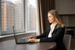 © Andrii Lysenko - Serious motivated caucasian businesswoman working in a bright office with a laptop near the window, a millennial woman in a stylish suit creates a new project