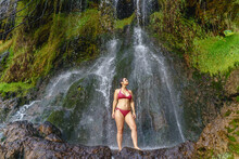 Full Body View Of Caucasian Woman In Swimsuit At Thermal Springs In Colombia. Horizontal Panoramic View Of Woman Underneath A Huge Waterfall At The Jungle In Colombia Travel Destination.
