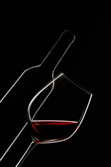 Wall Mural - Glass and bottle of red wine on a black background.