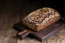 Brown Bread With Sunflower Seed On A Wooden Board And Black Backround