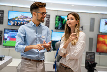 Portrait Of Salesman Helping To Woman To Buy A New Digital Device In Tech Shop
