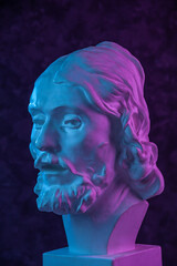 Colorful gypsum copy of ancient statue of John the Baptist head for artists on a dark textured background. Plaster sculpture man face. John baptized Jesus. Art poster in purple and blue bright colors.