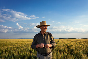 Portrait of senior farmer in wheat field at sunset.