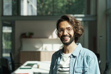 Portrait of young man with beard and eyeglasses Engineer employee worker of a Tech Creative Startup Company , standing in a modern office