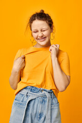 pretty girl gestures with hands grimace emotions yellow background unaltered