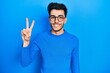 © Krakenimages.com - Young hispanic man wearing casual clothes and glasses showing and pointing up with fingers number two while smiling confident and happy.