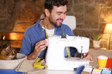 Wall Mural - Young man using sewing machine