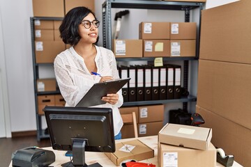 Poster - Young latin woman ecommerce business worker writing on clipboard at office