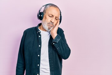 Poster - Handsome senior man with beard listening to music using headphones thinking looking tired and bored with depression problems with crossed arms.