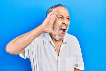 Canvas Print - Handsome senior man with beard wearing casual white shirt shouting and screaming loud to side with hand on mouth. communication concept.