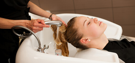 Wall Mural - Hair stylist at work - hairdresser washing hair to the customer before doing hairstyle in a professional salon