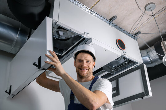 smiling hvac technician at work. ventilation, heating system maintenance and repair