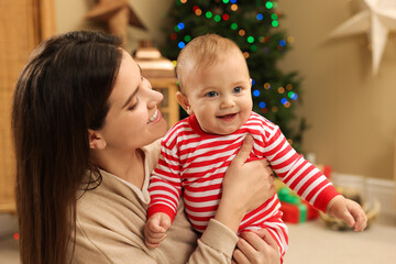 Wall Mural - Happy you mother with her cute baby in room decorated for Christmas. Winter holiday