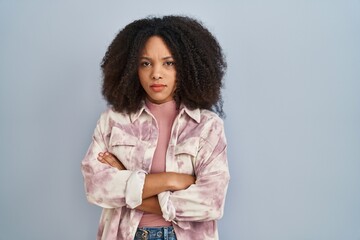 Poster - Young african american woman standing over blue background skeptic and nervous, disapproving expression on face with crossed arms. negative person.