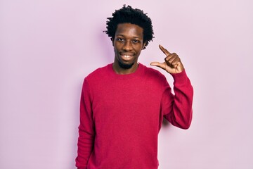 Sticker - Young african american man wearing casual clothes smiling and confident gesturing with hand doing small size sign with fingers looking and the camera. measure concept.