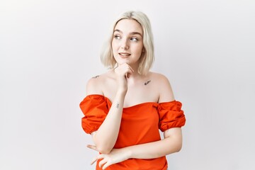 Sticker - Young caucasian woman standing over isolated background looking confident at the camera smiling with crossed arms and hand raised on chin. thinking positive.