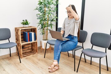 Canvas Print - Young asian nurse woman sitting at waiting room using laptop stressed and frustrated with hand on head, surprised and angry face