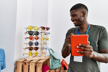 Wall Mural - Young african american man smiling confident using touchpad working at clothing store